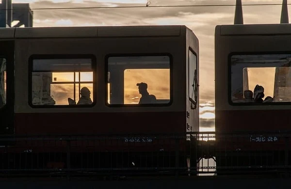 Menschen sitzen im Zugwaggon vor einem Sonnenuntergang
