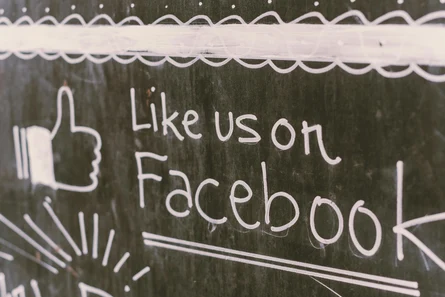 Tafel mit der Kreideaufschrift "Like us at facebook"