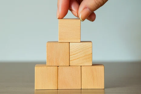 Hände stapeln eine Holzpyramide